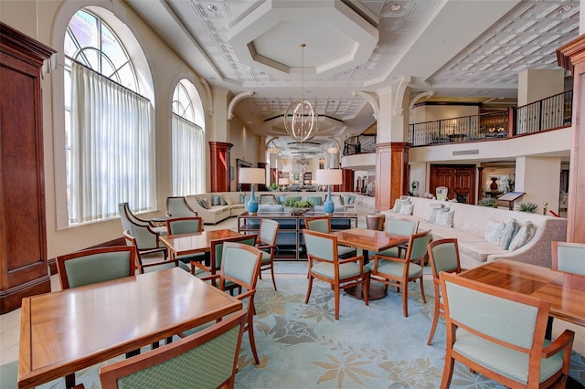 dining space with coffered ceiling, a chandelier, ornate columns, and a high ceiling