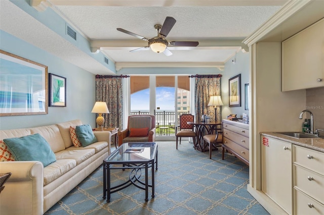 living room with dark carpet, ceiling fan, sink, and a textured ceiling