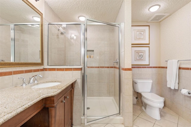 bathroom featuring tile walls, a textured ceiling, an enclosed shower, vanity, and toilet