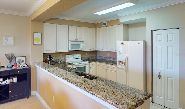 kitchen with white cabinets, white appliances, kitchen peninsula, stone countertops, and sink