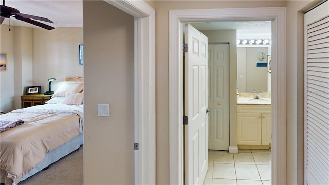 tiled bedroom with ceiling fan, sink, and ensuite bathroom