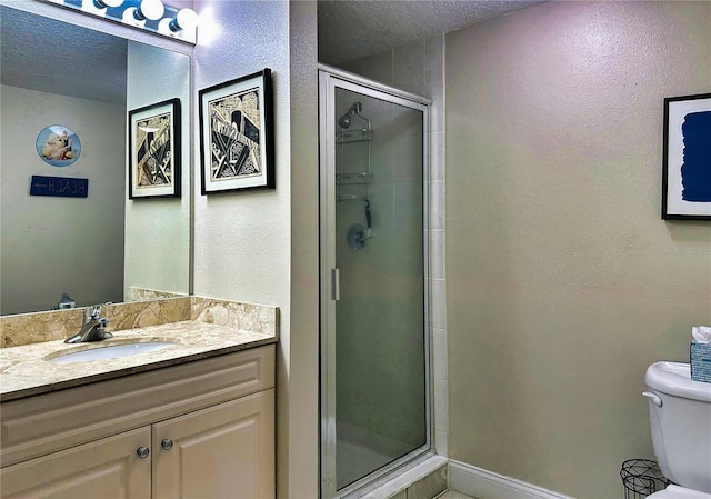 bathroom featuring a textured ceiling, a shower with door, vanity, and toilet