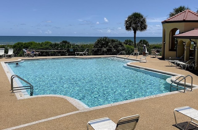 view of swimming pool with a water view and a patio area