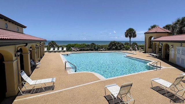 view of pool with a water view and a patio area