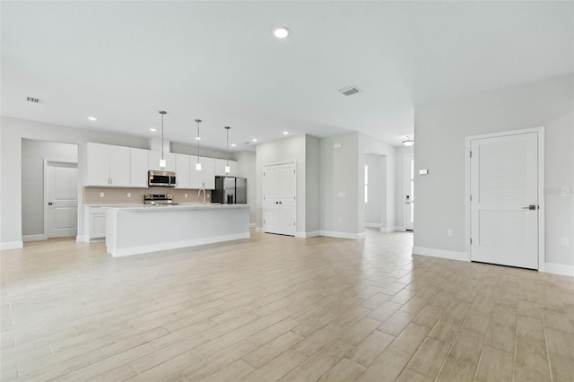 unfurnished living room featuring light wood-type flooring and sink