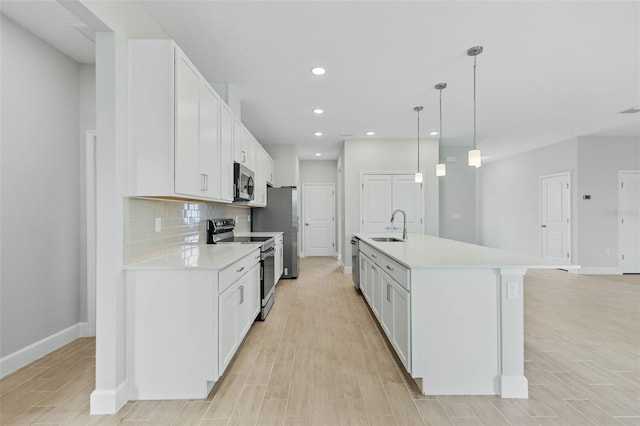 kitchen with a center island with sink, light hardwood / wood-style floors, white cabinetry, and stainless steel appliances