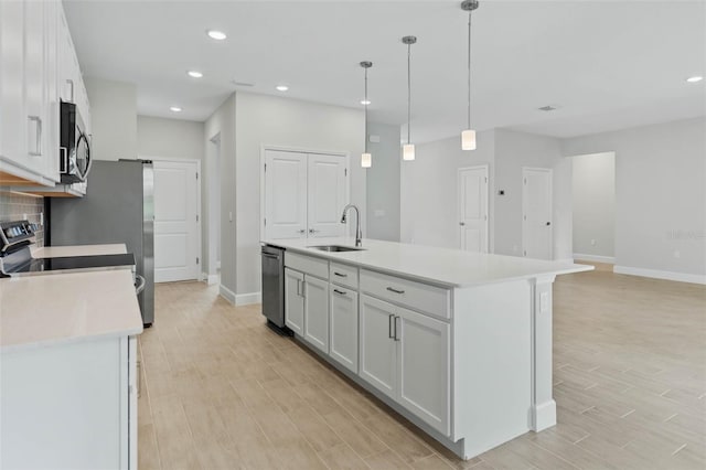 kitchen with white cabinets, a center island with sink, light wood-type flooring, and sink