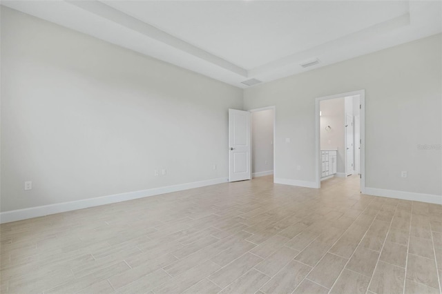 unfurnished room with light hardwood / wood-style flooring and a raised ceiling