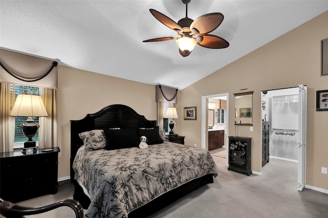 bedroom with ceiling fan, light carpet, vaulted ceiling, and ensuite bathroom