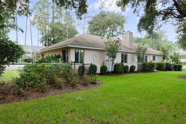 back of house featuring a lanai and a yard