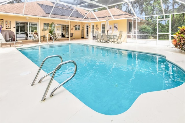 view of pool with a patio, ceiling fan, and glass enclosure