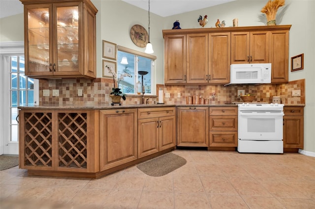 kitchen with white appliances, a healthy amount of sunlight, vaulted ceiling, and hanging light fixtures