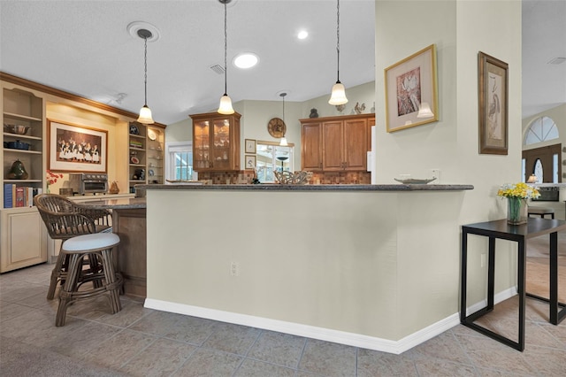 kitchen featuring tile patterned floors, a kitchen breakfast bar, hanging light fixtures, kitchen peninsula, and built in shelves