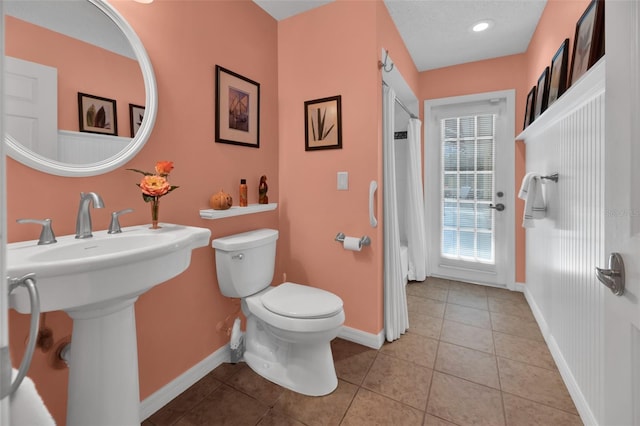 bathroom featuring tile patterned floors, sink, curtained shower, and toilet