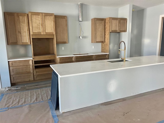 kitchen featuring an island with sink, sink, black electric stovetop, and a textured ceiling