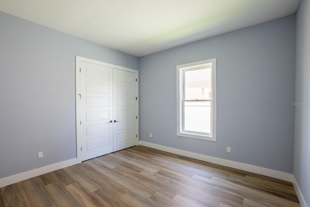 72 Flemingwood Ln, Palm Coast, FL 32137 - unfurnished bedroom with wood finished floors, a closet, and baseboards
