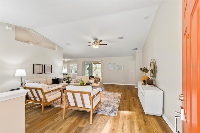 living room with wood-type flooring, vaulted ceiling, and ceiling fan