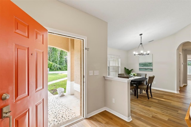 entryway with a notable chandelier, lofted ceiling, and hardwood / wood-style flooring