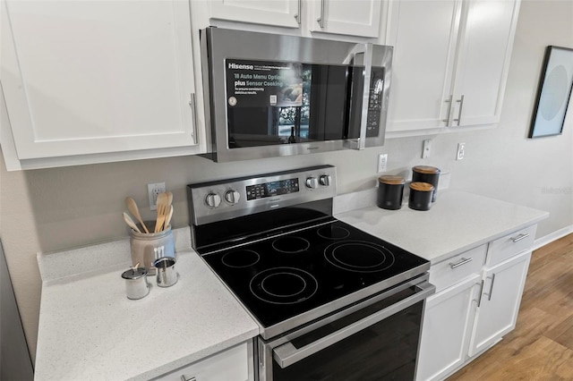 kitchen with light wood-type flooring, stainless steel appliances, and white cabinets