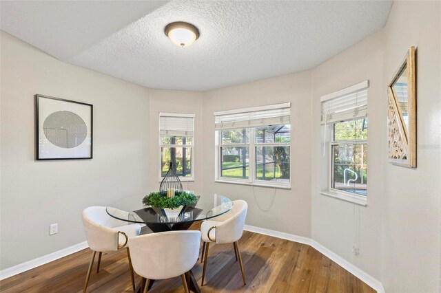 dining area featuring a textured ceiling, wood-type flooring, and a wealth of natural light