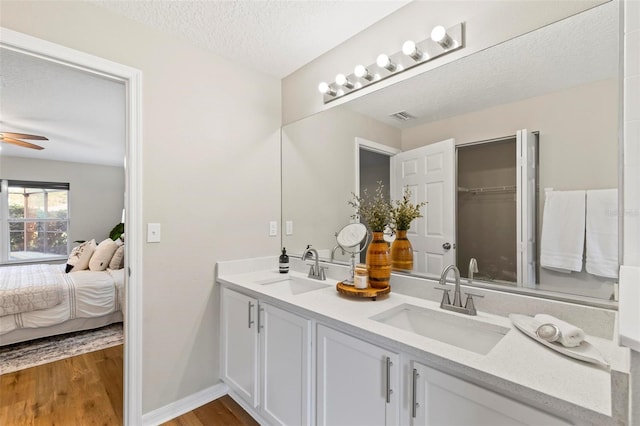 bathroom featuring ceiling fan, vanity, a textured ceiling, and hardwood / wood-style flooring