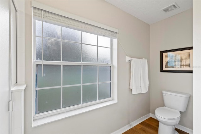 bathroom with hardwood / wood-style flooring, toilet, and a textured ceiling