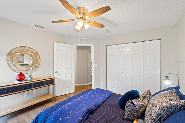 bedroom with a closet, wood-type flooring, ceiling fan, and a textured ceiling