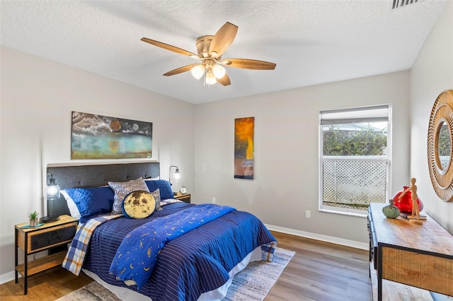 bedroom featuring wood-type flooring, ceiling fan, and a textured ceiling