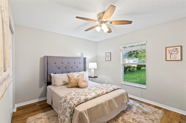 bedroom with a textured ceiling, hardwood / wood-style floors, and ceiling fan