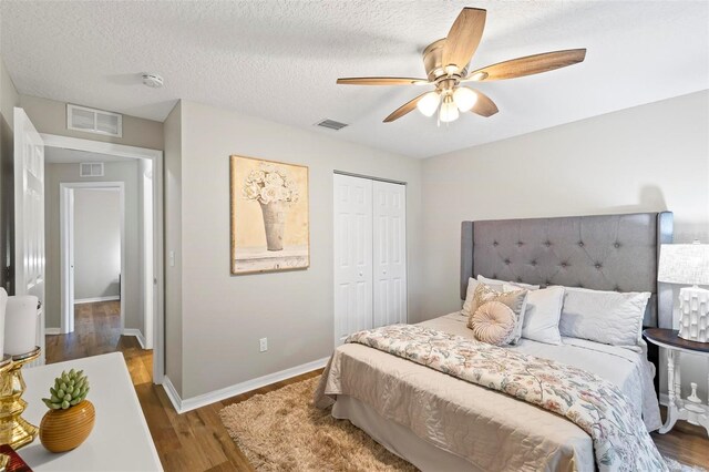 bedroom with a closet, ceiling fan, hardwood / wood-style floors, and a textured ceiling