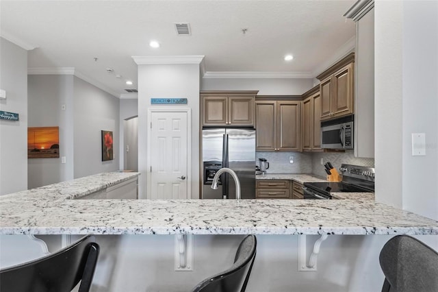 kitchen featuring appliances with stainless steel finishes, kitchen peninsula, a kitchen breakfast bar, and tasteful backsplash