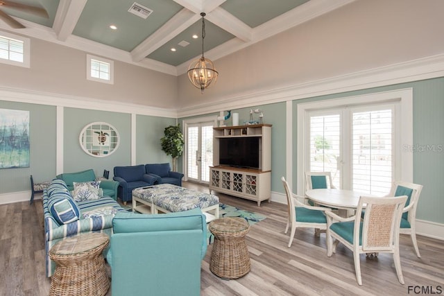 living room with coffered ceiling, a towering ceiling, beam ceiling, hardwood / wood-style floors, and a notable chandelier