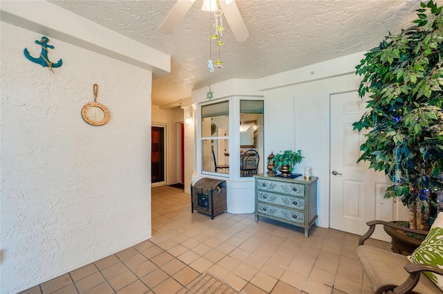 unfurnished room with a textured ceiling, light tile patterned floors, and ceiling fan