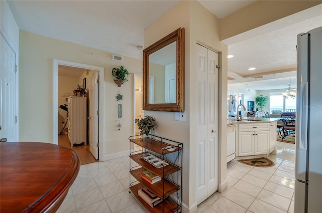 corridor with a chandelier, light tile patterned floors, and sink