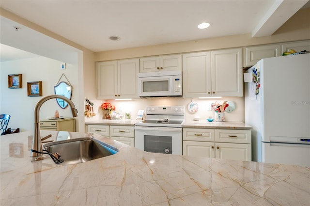 kitchen with white appliances, light stone counters, and sink