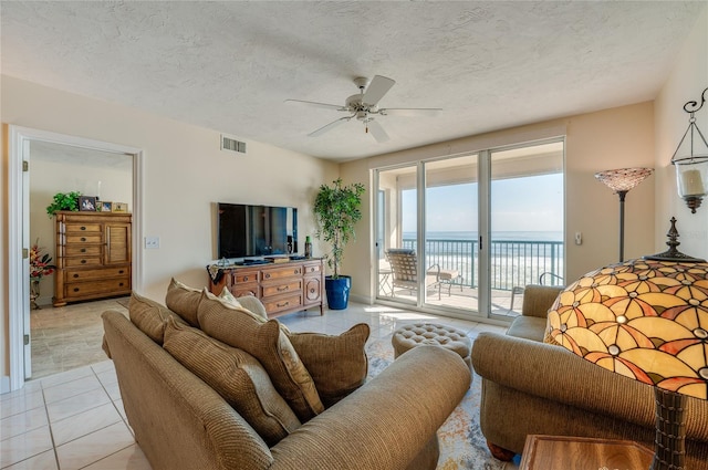 tiled living room featuring ceiling fan and a textured ceiling