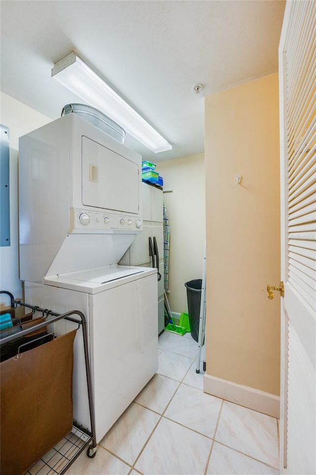 laundry room featuring light tile patterned flooring, stacked washer / dryer, and electric panel