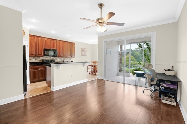 kitchen featuring ceiling fan, tasteful backsplash, hardwood / wood-style flooring, a kitchen breakfast bar, and white fridge