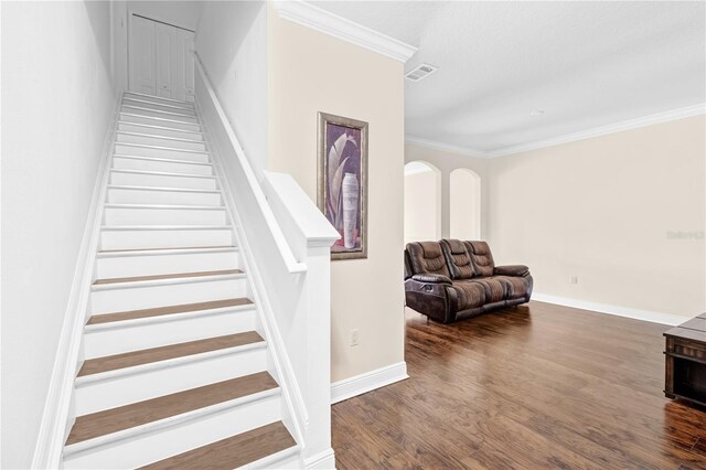 staircase with wood-type flooring and crown molding