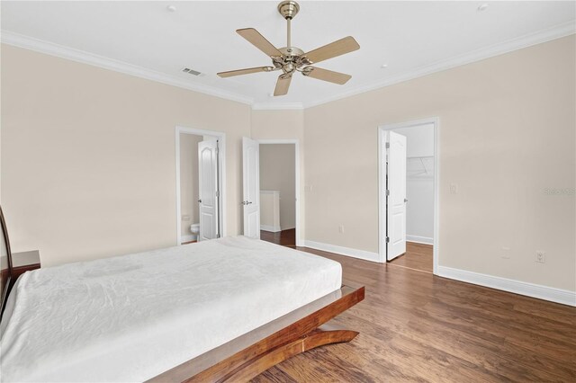 bedroom featuring a closet, dark hardwood / wood-style floors, a walk in closet, crown molding, and ceiling fan