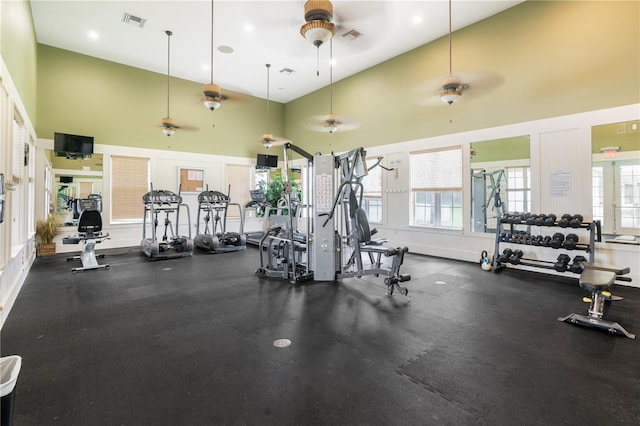 gym featuring ceiling fan and a towering ceiling