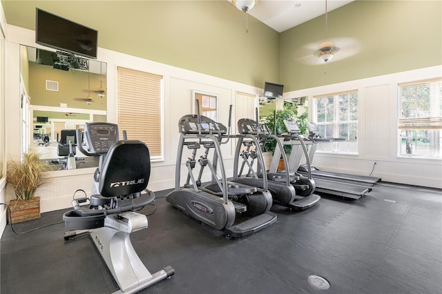 exercise room with a towering ceiling and ceiling fan