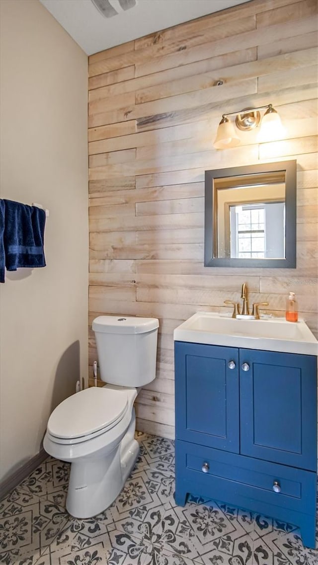 bathroom featuring tile patterned floors, wood walls, vanity, and toilet