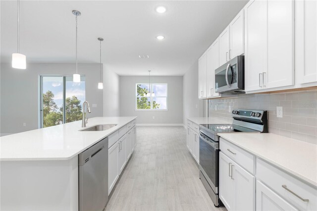 kitchen with a wealth of natural light, white cabinets, appliances with stainless steel finishes, and sink