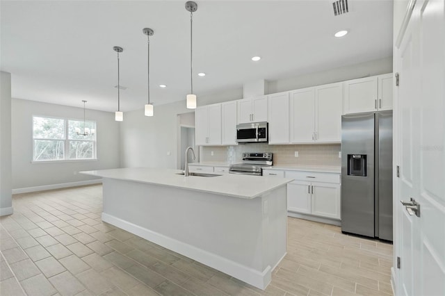 kitchen with appliances with stainless steel finishes, a center island with sink, sink, and white cabinets