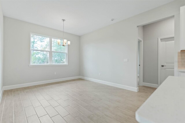 unfurnished dining area with an inviting chandelier and light wood-type flooring