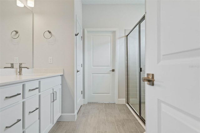 bathroom with hardwood / wood-style floors, walk in shower, and vanity