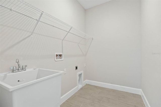 washroom featuring hookup for a washing machine, light hardwood / wood-style floors, hookup for an electric dryer, and sink