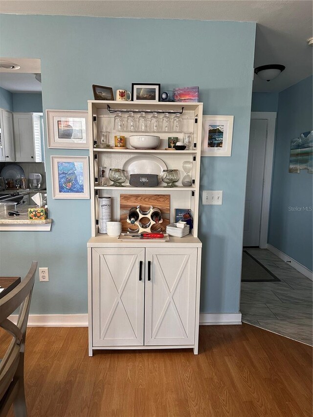 bar featuring white cabinets and hardwood / wood-style flooring