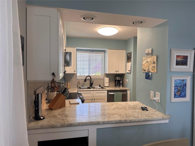 kitchen featuring stainless steel dishwasher, sink, light stone counters, and white cabinets